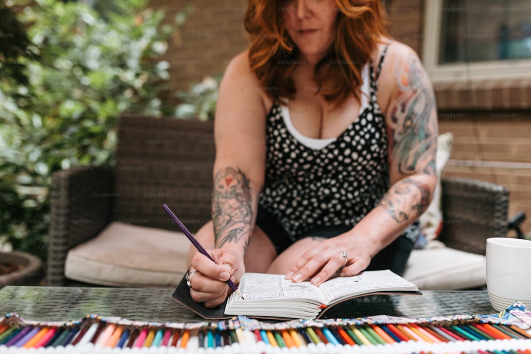 Overhead view of a finished masculine coloring page showing a detailed cityscape in urban colors with grays blues and warm browns, colored pencils arranged nearby, satisfying completed architectural artwork, clean modern desk setup