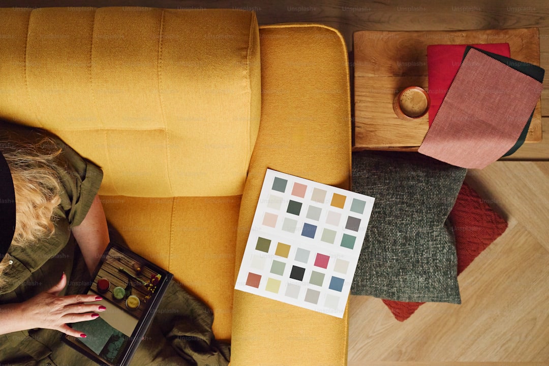 Simple coloring book open on a couch cushion with a few colored pencils, partially colored page with large simple shapes, cozy living room setting, soft natural light, relaxed and unpressured scene, self-care and recovery concept