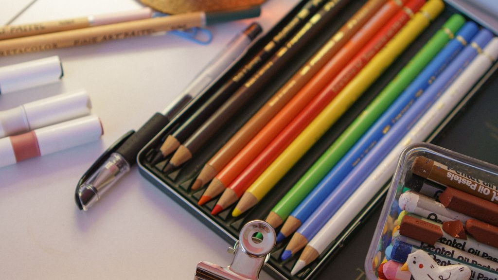 Colored pencils organized in a desktop holder next to an open coloring book