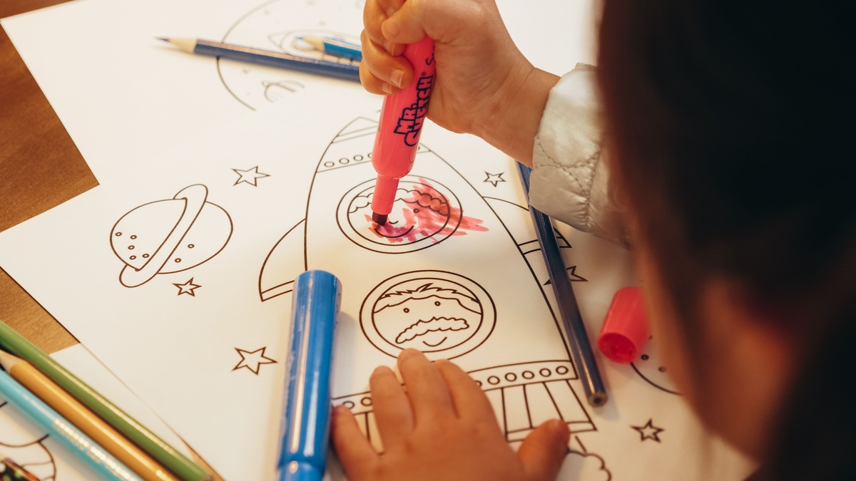 Hands using Crayola Color and Detail markers on an adult coloring book page, broad tip filling a large area with smooth even color, close-up lifestyle photography