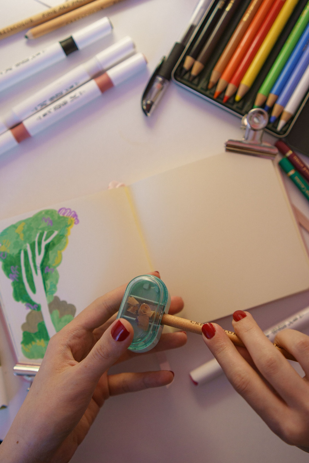 Kum brass pocket sharpener next to colored pencils in a travel coloring kit