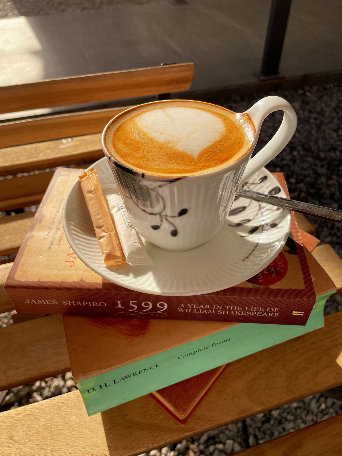Cozy outdoor cafe scene with coffee and a book on a wooden table