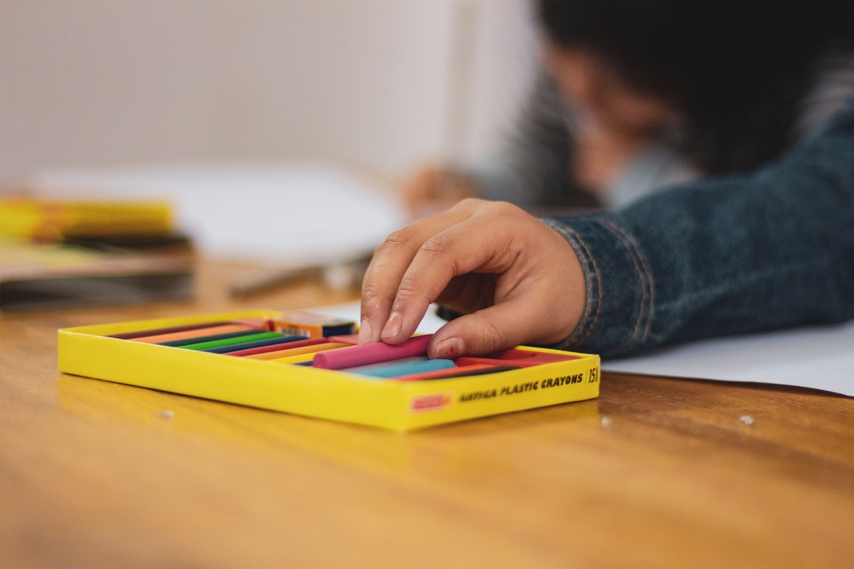 Hands picking out colored pencils from a small set, choosing four to five colors for a first coloring session, warm and approachable mood, close-up lifestyle photography