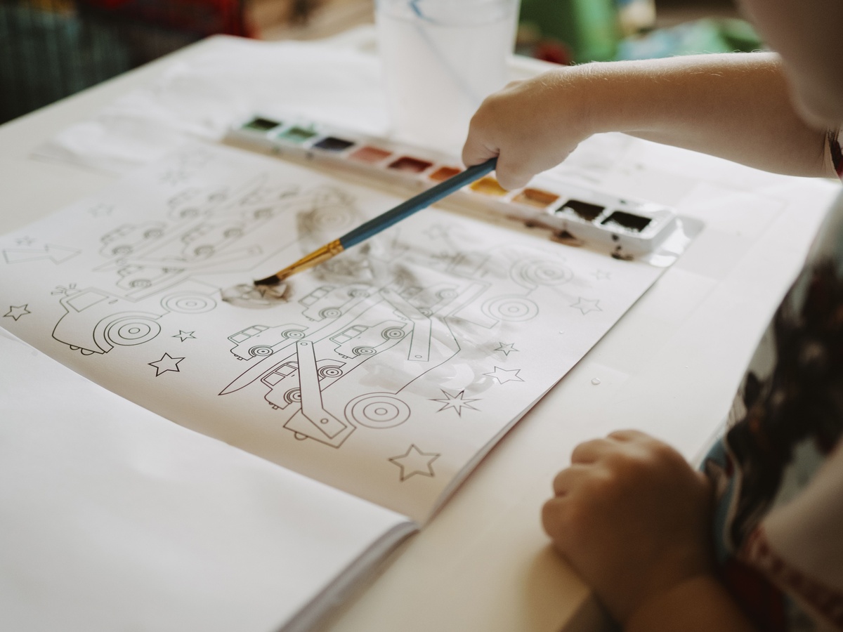 A partially colored beginner page showing simple but satisfying color choices, colored pencils resting on the book, warm afternoon light, encouraging and hopeful mood, lifestyle photography