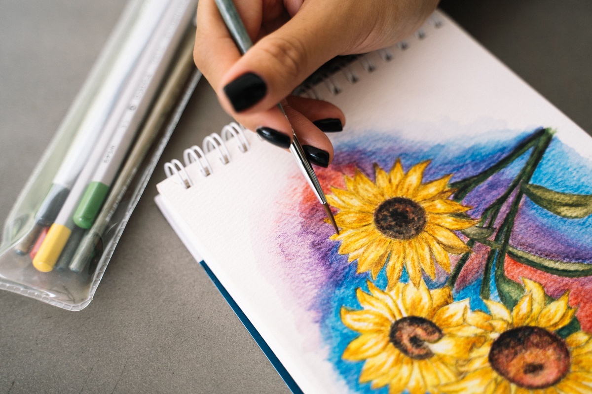 Caran d'Ache Museum Aquarelle watercolor pencils showing vibrant swatches before and after water activation, premium art supplies on a white surface