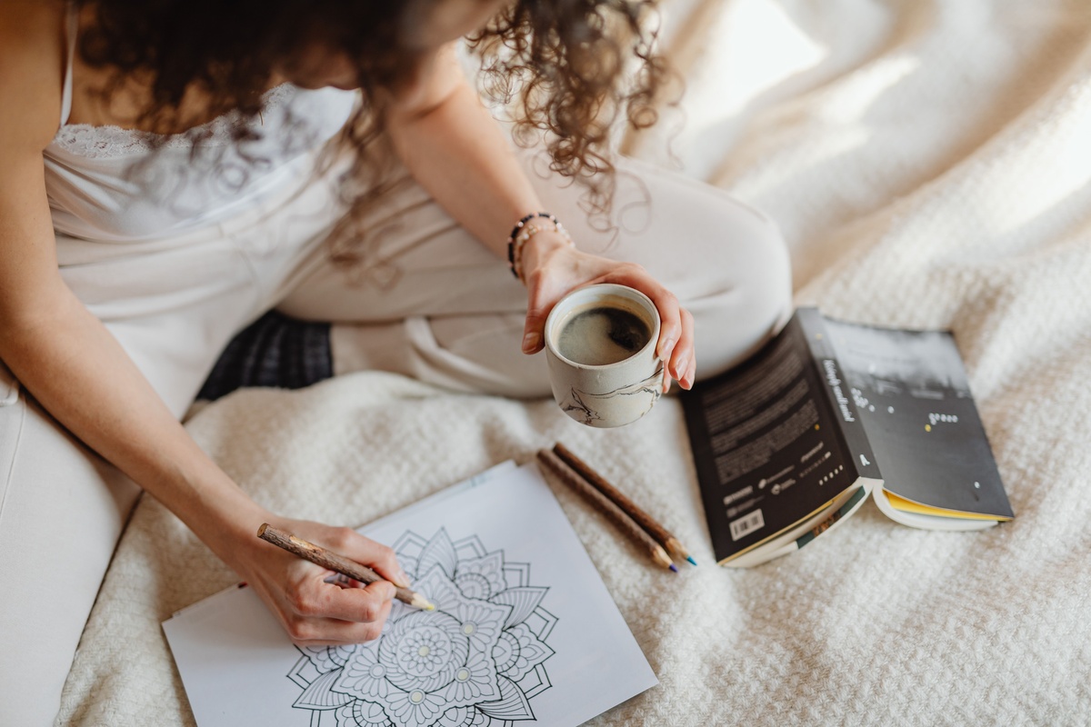 A winter coloring kit with colored pencils, a mindfulness coloring book, and a light therapy box on a bedside table, morning routine setup, warm and inviting, close-up product photography