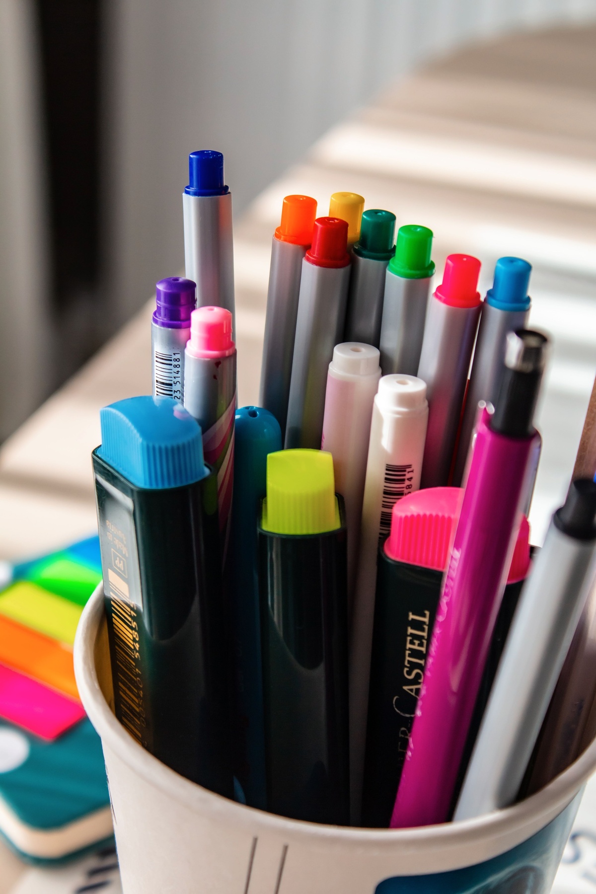 Colored pencils and markers arranged in cups on a desk