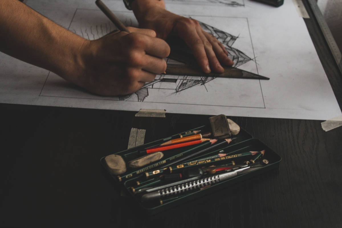 Art markers and drafting pencils laid out on white surface