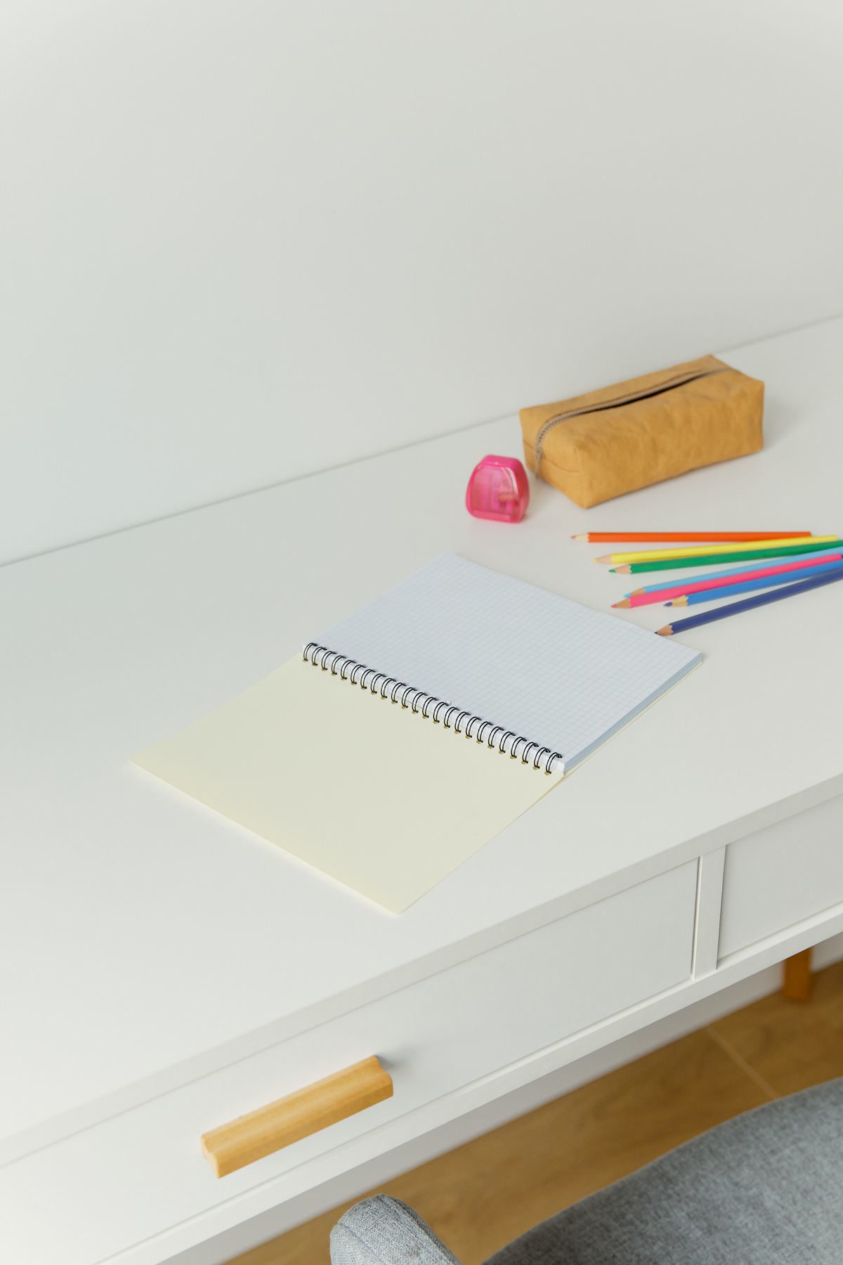 Several adult coloring books with detailed patterns spread on a desk beside colored pencils and a cup of tea