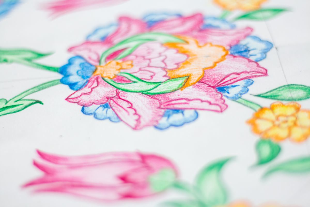 Hands carefully coloring within the lines of a detailed floral page with Prismacolor pencils, close-up view