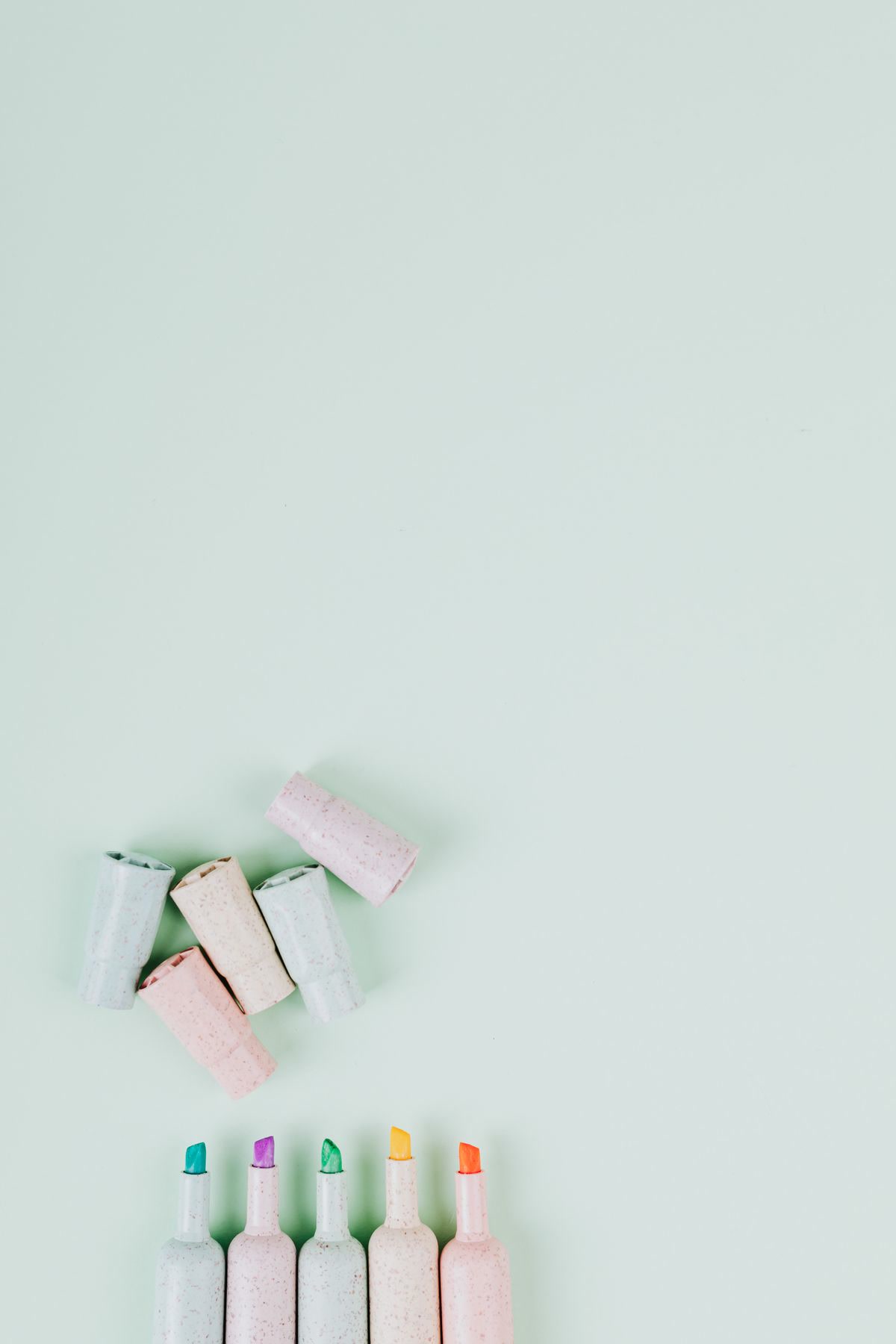 Colorful markers with caps arranged in a flat lay on a neutral background