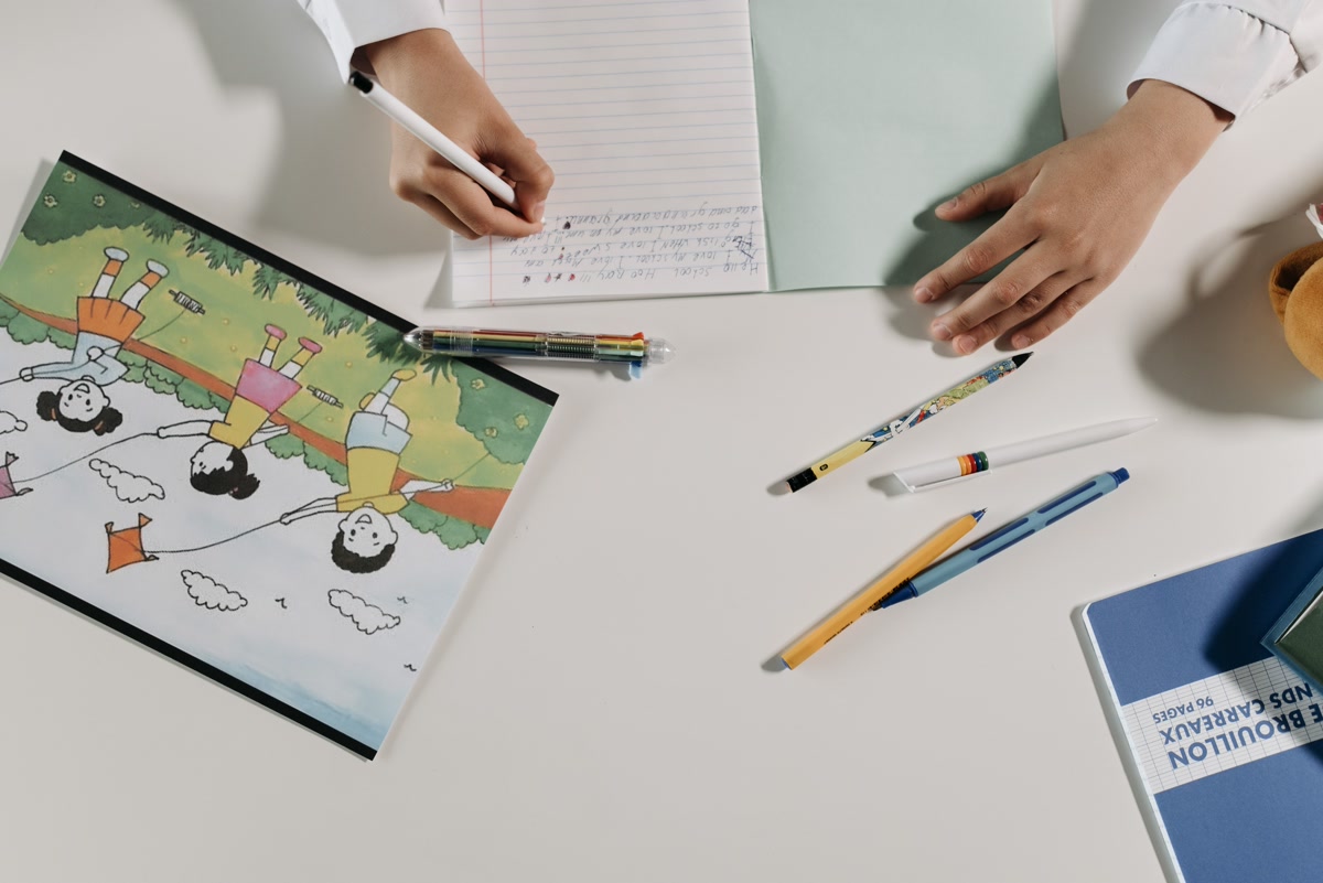 A desk drawer opened to reveal a small coloring kit with a pocket-sized coloring book, a zip pouch of colored pencils, and an eraser, neat and discreet desk storage, close-up product photography