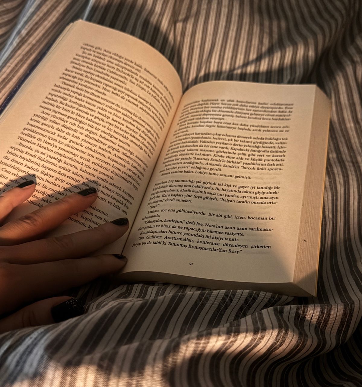 Person relaxing in bed with an open book, warm soft lighting, cozy bedroom scene for evening wind-down