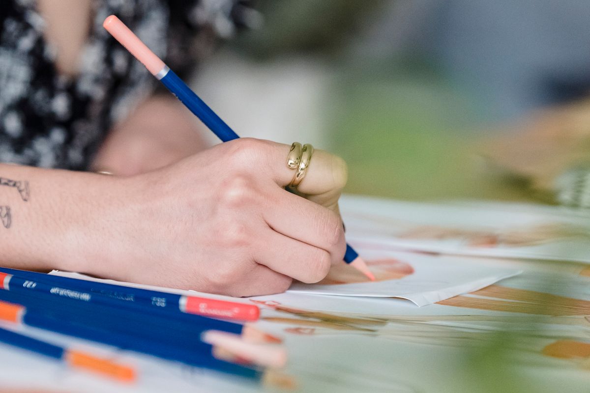 Artist coloring at a desk with colored pencils in a workspace