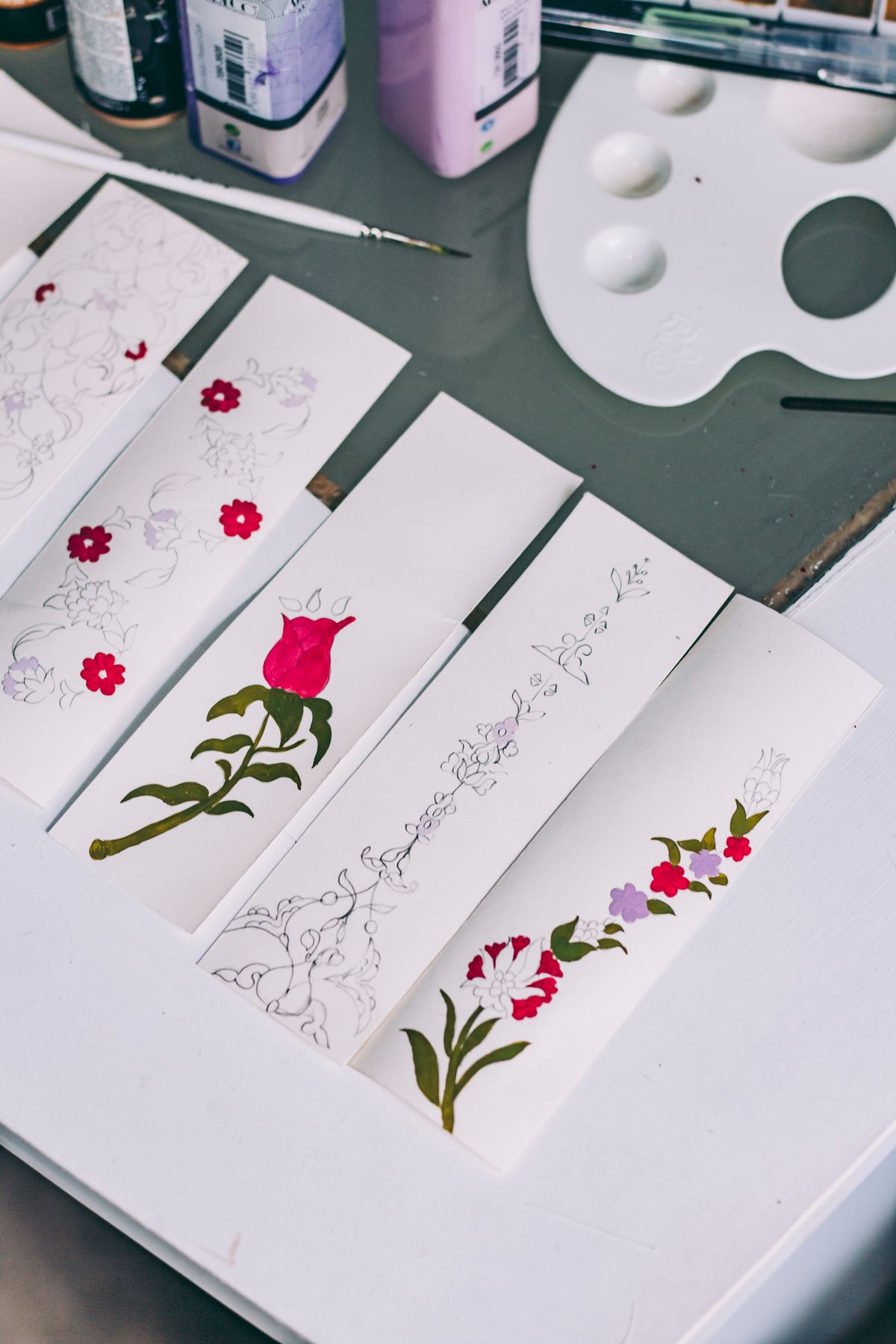 Art supplies and hand-colored floral designs on a table, showcasing what quality markers can achieve