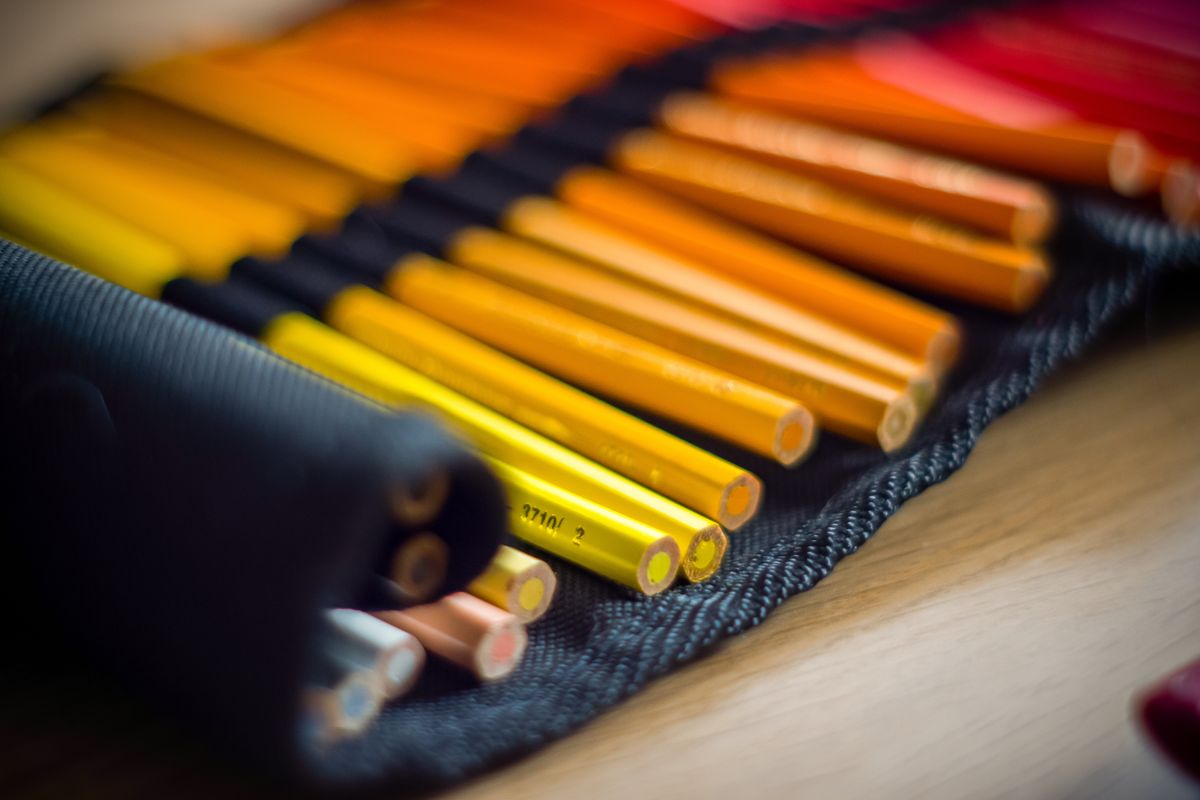 Close-up of vibrant colored pencils on a textured surface, showing rich color saturation achievable with quality art supplies